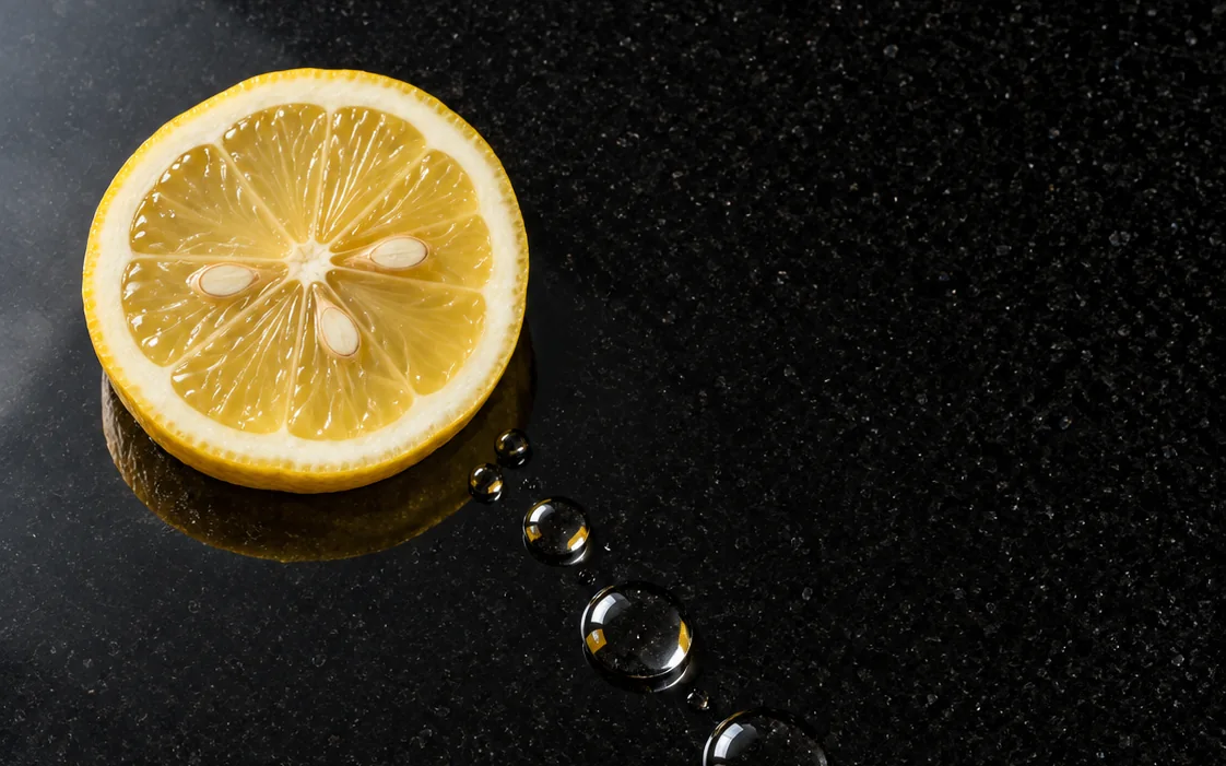 Meia rodela de limão e gotas de suco sobre o granito Preto São Gabriel polido